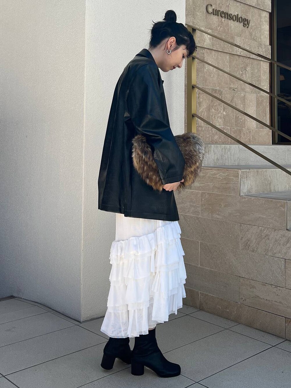 ホワイト系のタンクトップ、ホワイト系のスカート、ブラック系のブルゾンを着用したレディースの夏コーディネートの3枚目の写真