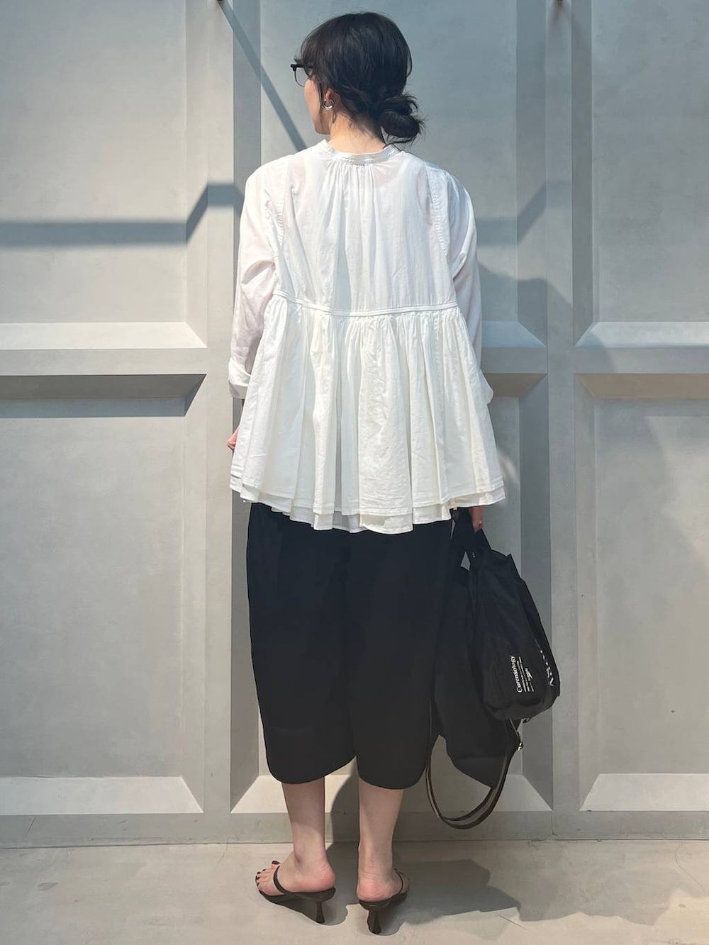 ブラック系のトートバッグ、ホワイト系のシャツ/ブラウス、ブラック系のその他パンツを着用したレディースの春コーディネートの3枚目の写真
