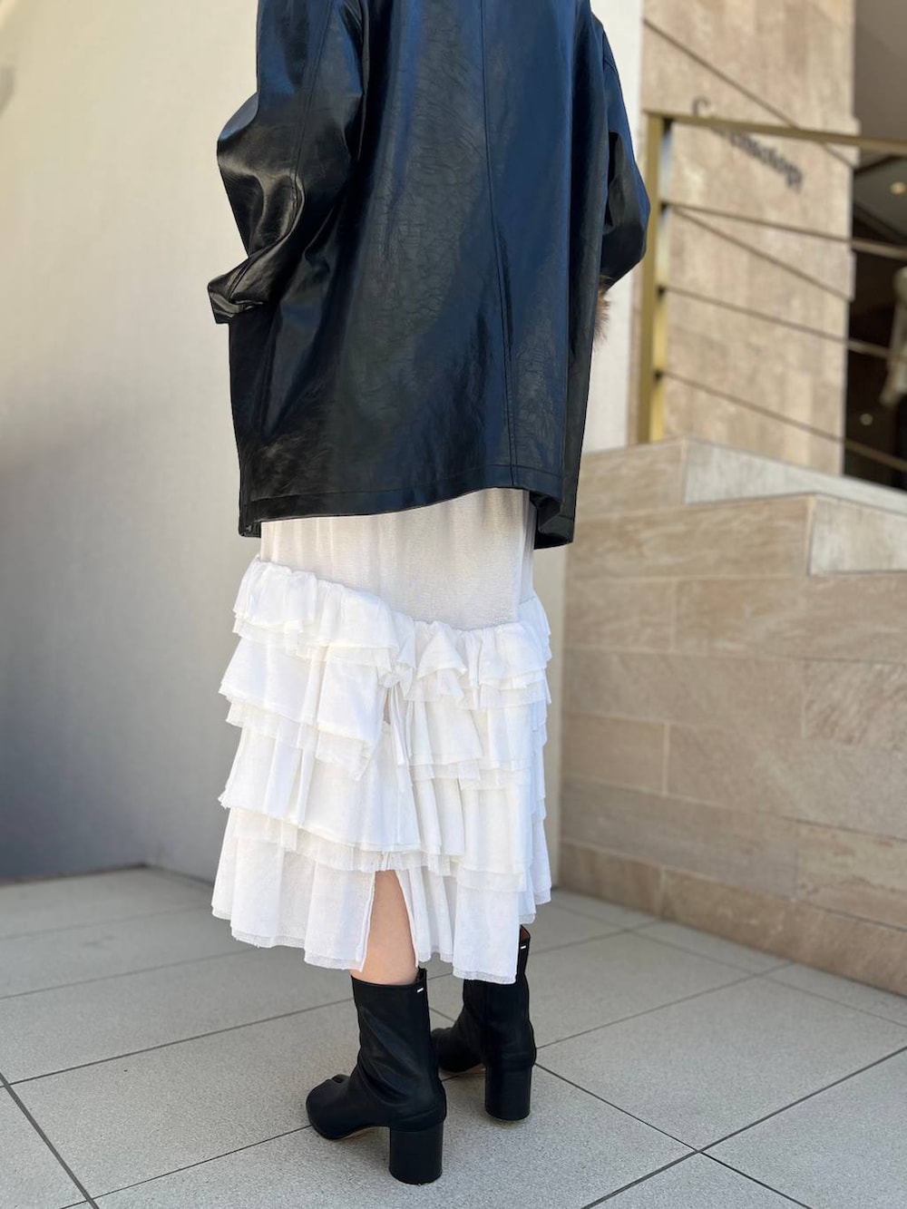 ホワイト系のタンクトップ、ホワイト系のスカート、ブラック系のブルゾンを着用したレディースの夏コーディネートの9枚目の写真