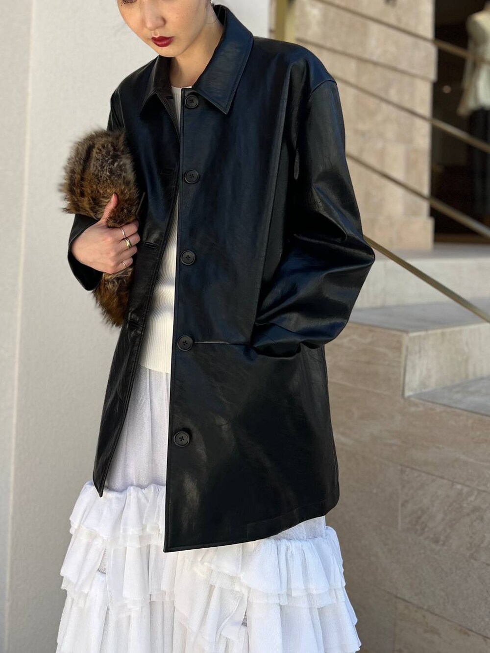 ホワイト系のタンクトップ、ホワイト系のスカート、ブラック系のブルゾンを着用したレディースの夏コーディネートの4枚目の写真