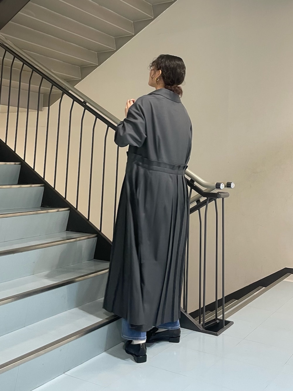 シルバー系のハンドバッグ、グレー系のワンピース、ブラック系のローファーを着用したレディースの春コーディネートの4枚目の写真