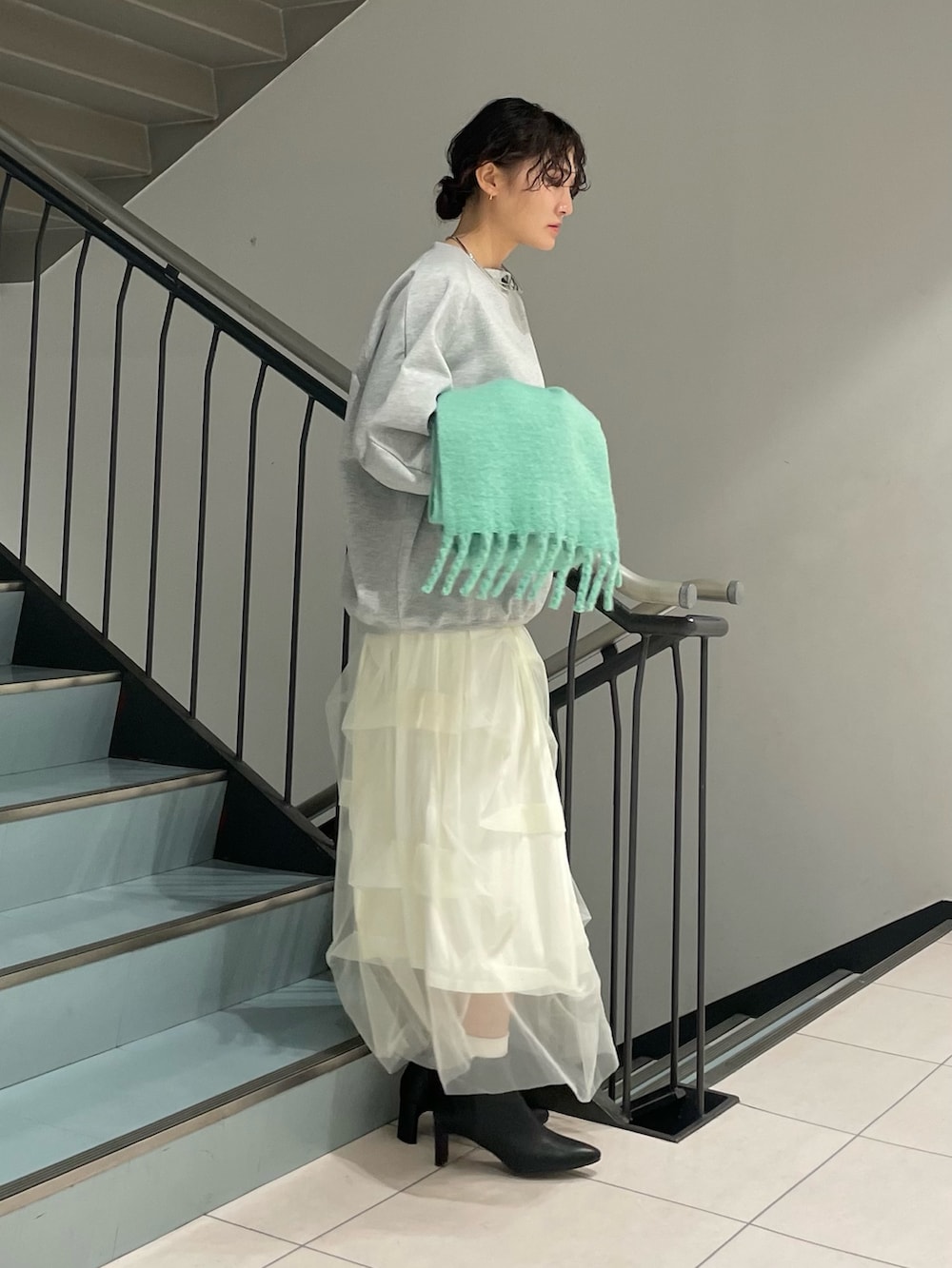 グレー系のスウェット、ホワイト系のスカート、ブラック系のブーツを着用したレディースの秋コーディネートの3枚目の写真