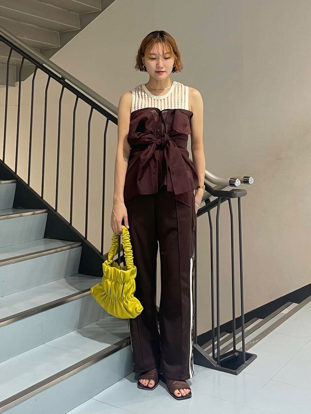 イエロー系のハンドバッグ、レッド系のシャツ/ブラウス、ブラウン系のサンダルを着用したレディースの夏コーディネートの2枚目の写真