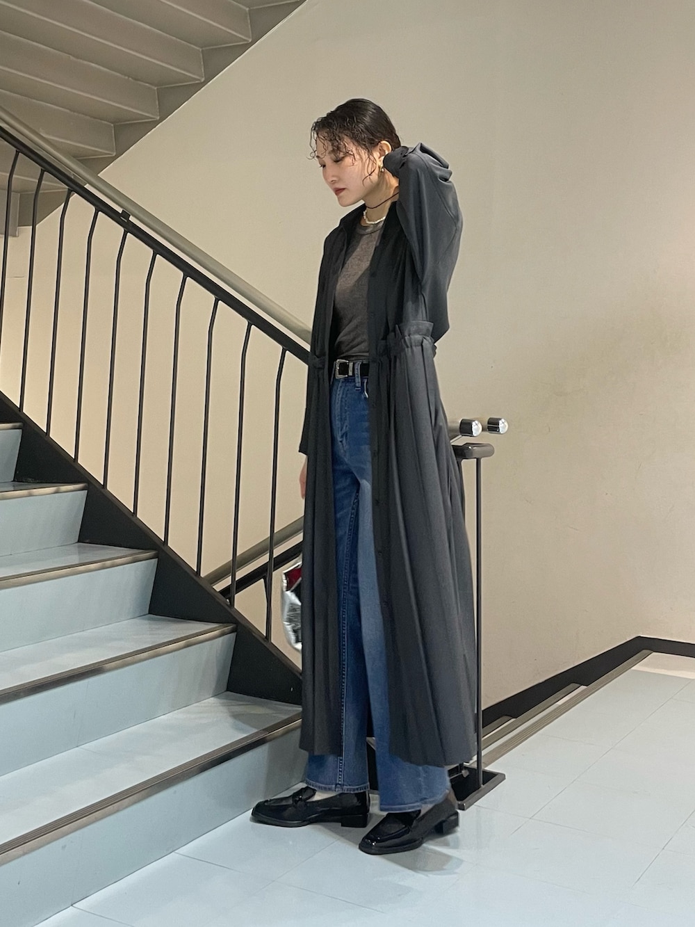 シルバー系のハンドバッグ、グレー系のワンピース、ブラック系のローファーを着用したレディースの春コーディネートの3枚目の写真