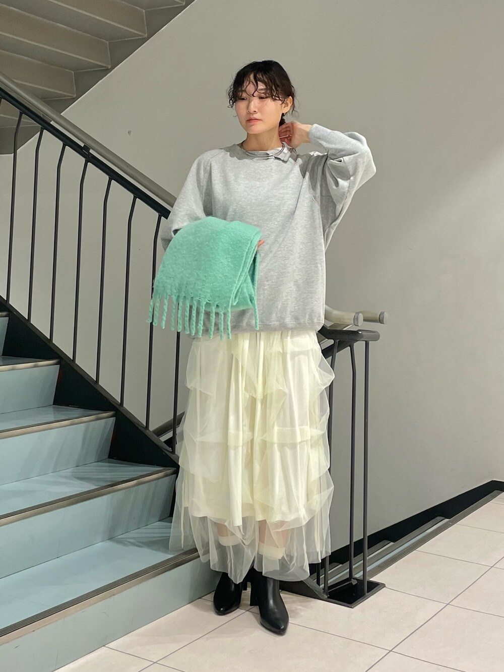 グレー系のスウェット、ホワイト系のスカート、ブラック系のブーツを着用したレディースの秋コーディネートの2枚目の写真