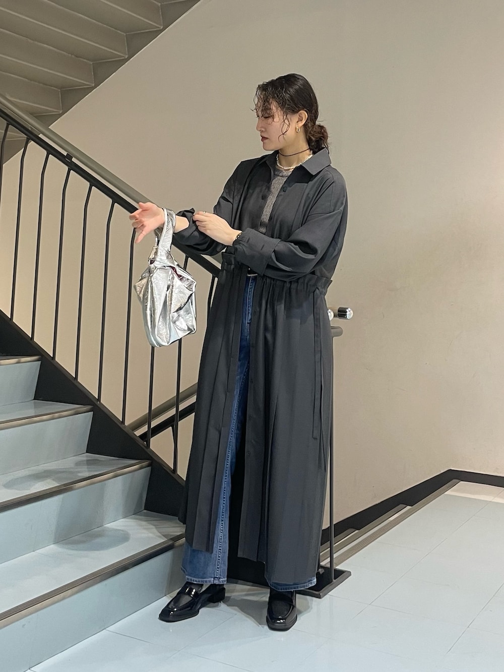 シルバー系のハンドバッグ、グレー系のワンピース、ブラック系のローファーを着用したレディースの春コーディネートの2枚目の写真