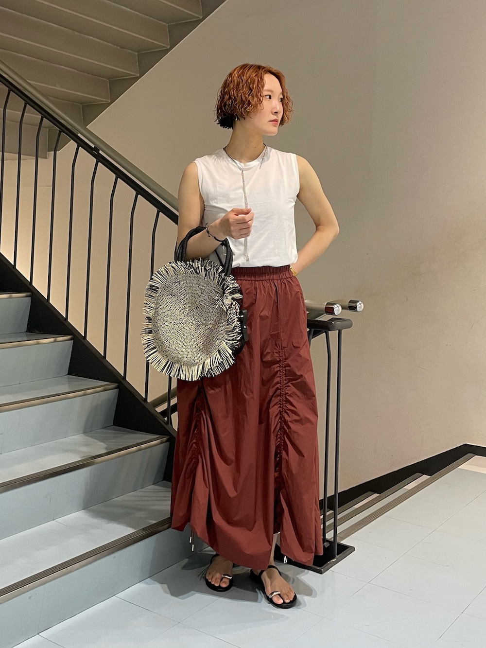 レッド系のスカート、ブラック系のハンドバッグ、ブラック系のサンダルを着用したレディースの夏コーディネートの2枚目の写真