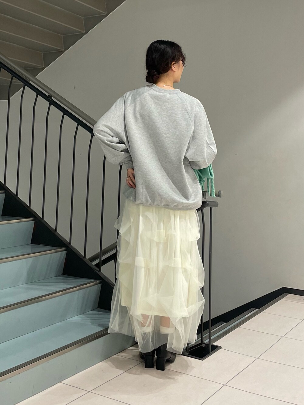 グレー系のスウェット、ホワイト系のスカート、ブラック系のブーツを着用したレディースの秋コーディネートの4枚目の写真