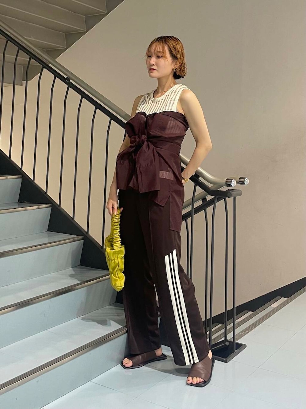 イエロー系のハンドバッグ、レッド系のシャツ/ブラウス、ブラウン系のサンダルを着用したレディースの夏コーディネートの3枚目の写真