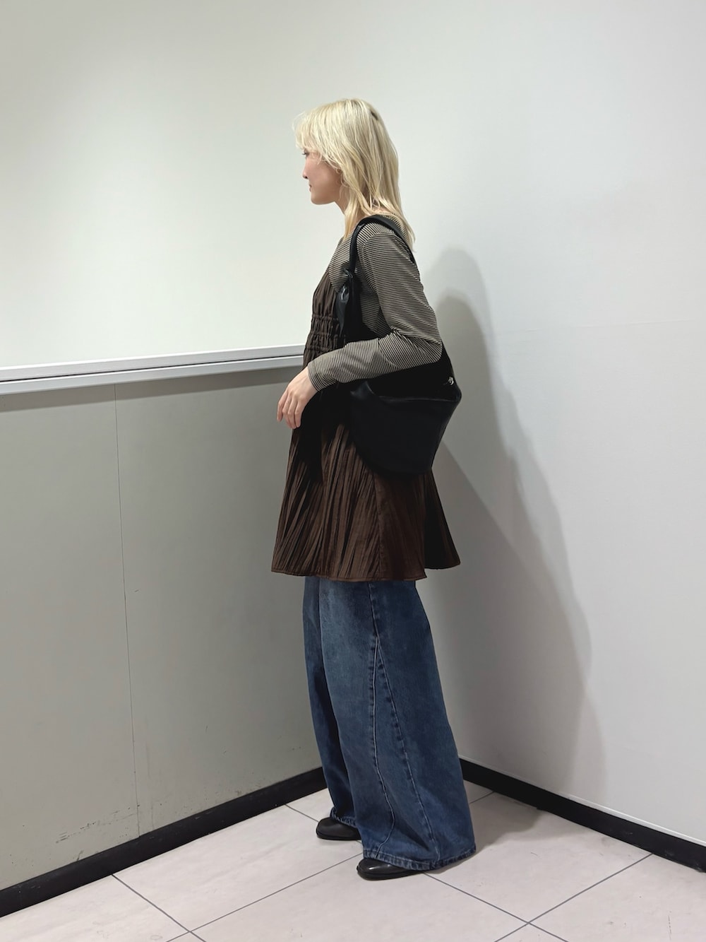 ベージュ系のキャミソール、ブラウン系のワンピース、ブルー系のデニムパンツを着用したレディースの春コーディネートの3枚目の写真