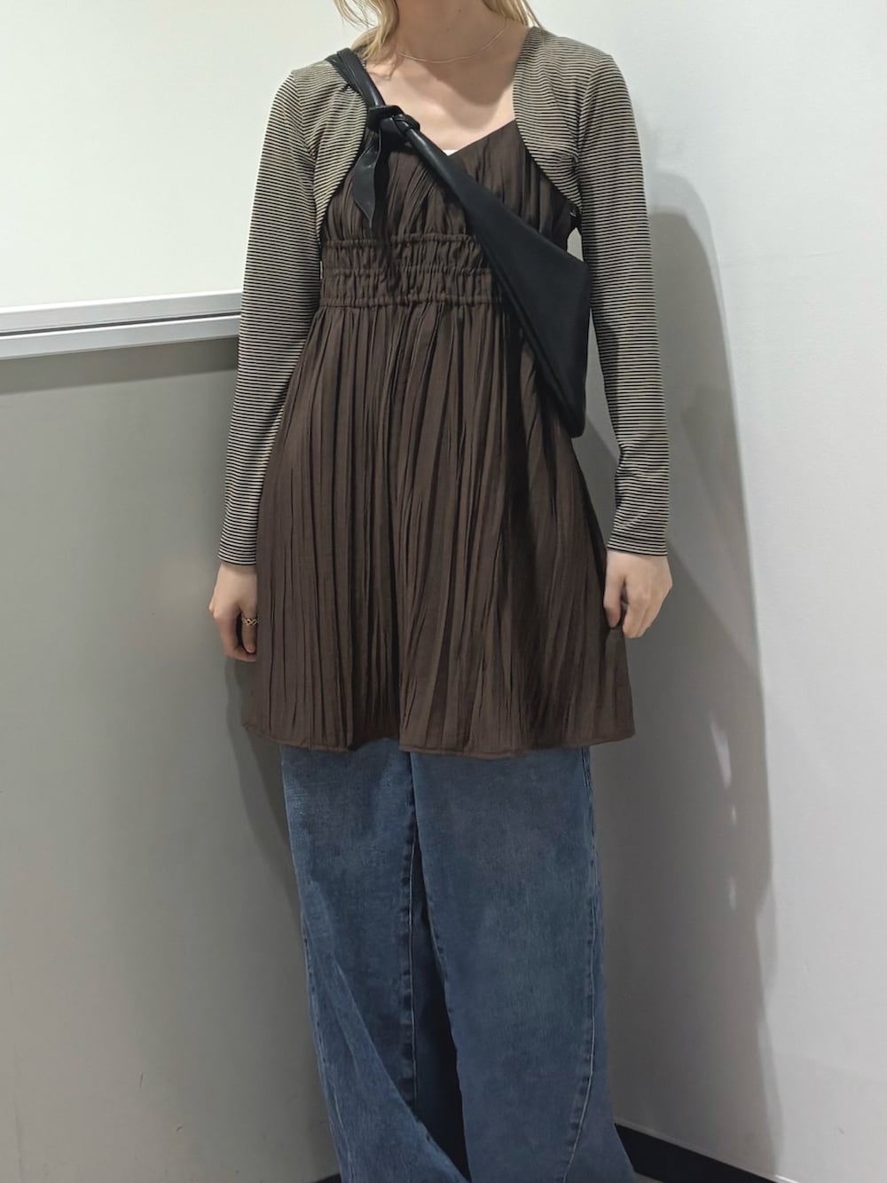 ベージュ系のキャミソール、ブラウン系のワンピース、ブルー系のデニムパンツを着用したレディースの春コーディネートの4枚目の写真