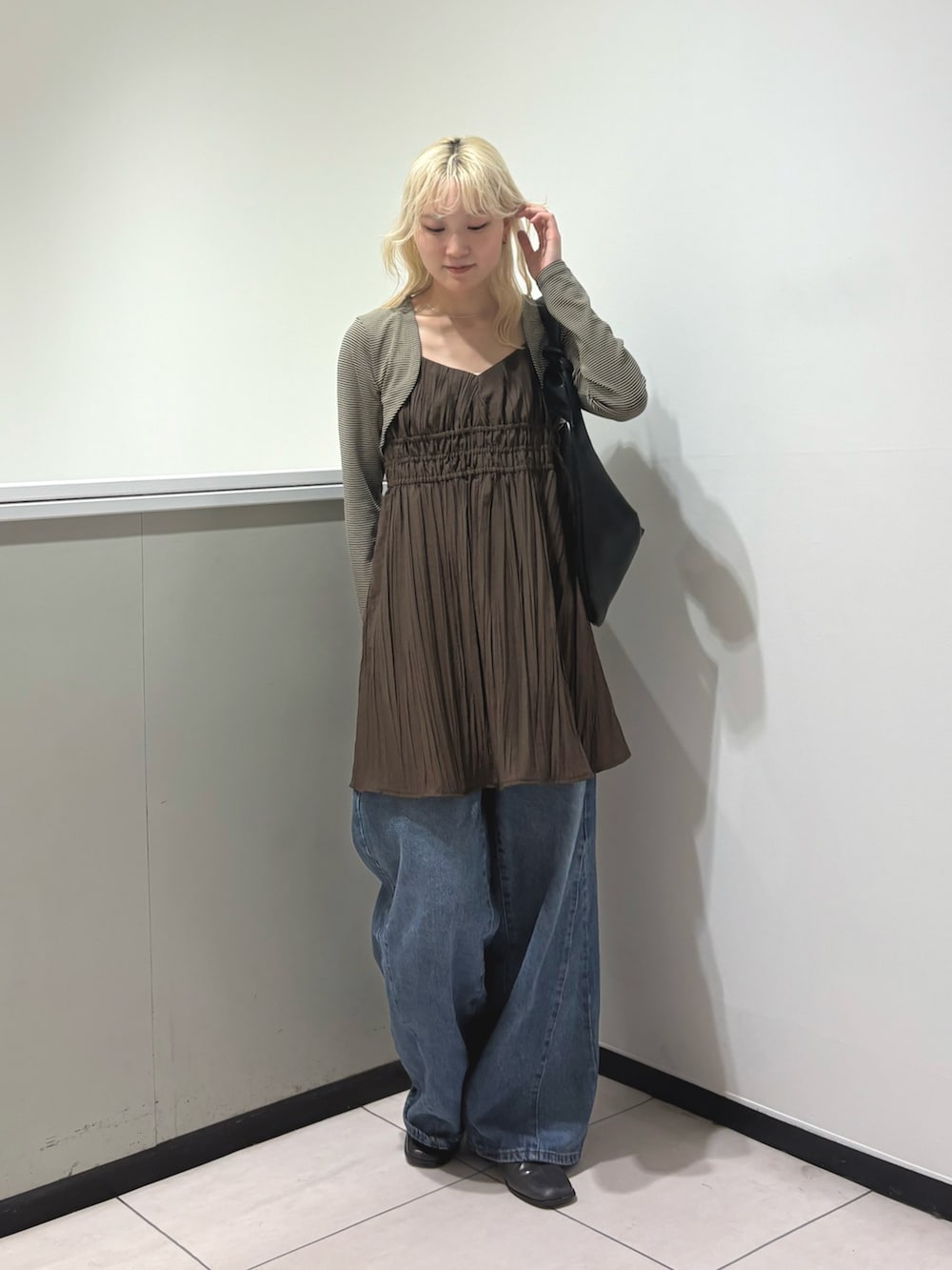 ベージュ系のキャミソール、ブラウン系のワンピース、ブルー系のデニムパンツを着用したレディースの春コーディネートの2枚目の写真