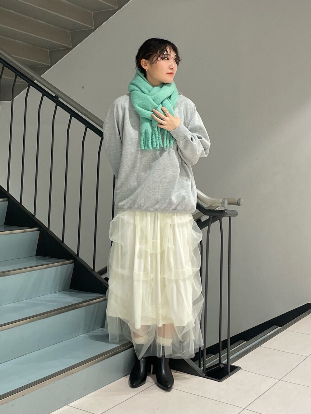 グレー系のスウェット、ホワイト系のスカート、ブラック系のブーツを着用したレディースの秋コーディネートの5枚目の写真