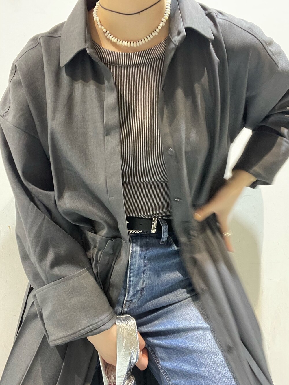 シルバー系のハンドバッグ、グレー系のワンピース、ブラック系のローファーを着用したレディースの春コーディネートの5枚目の写真