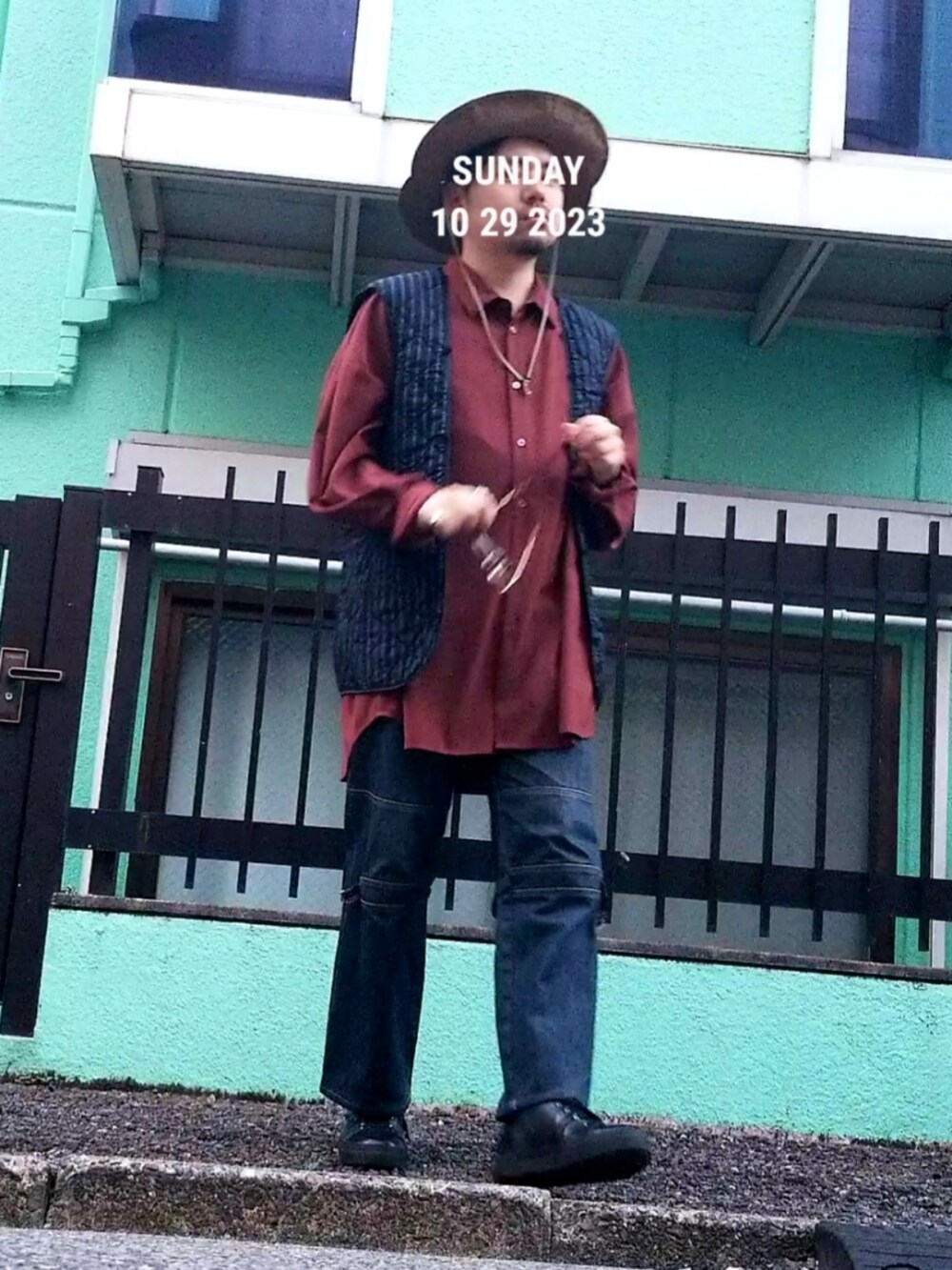 レッド系のシャツ/ブラウス、ブルー系のデニムパンツ、ベージュ系のハットを着用したメンズの秋コーディネートの2枚目の写真