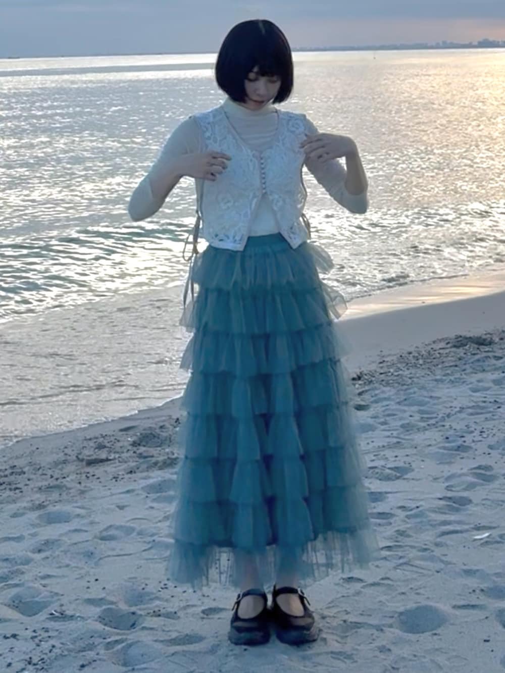 ブルー系のスカート、ブラック系のシューズ、ベージュ系のトップスを着用したレディースの夏コーディネートの4枚目の写真