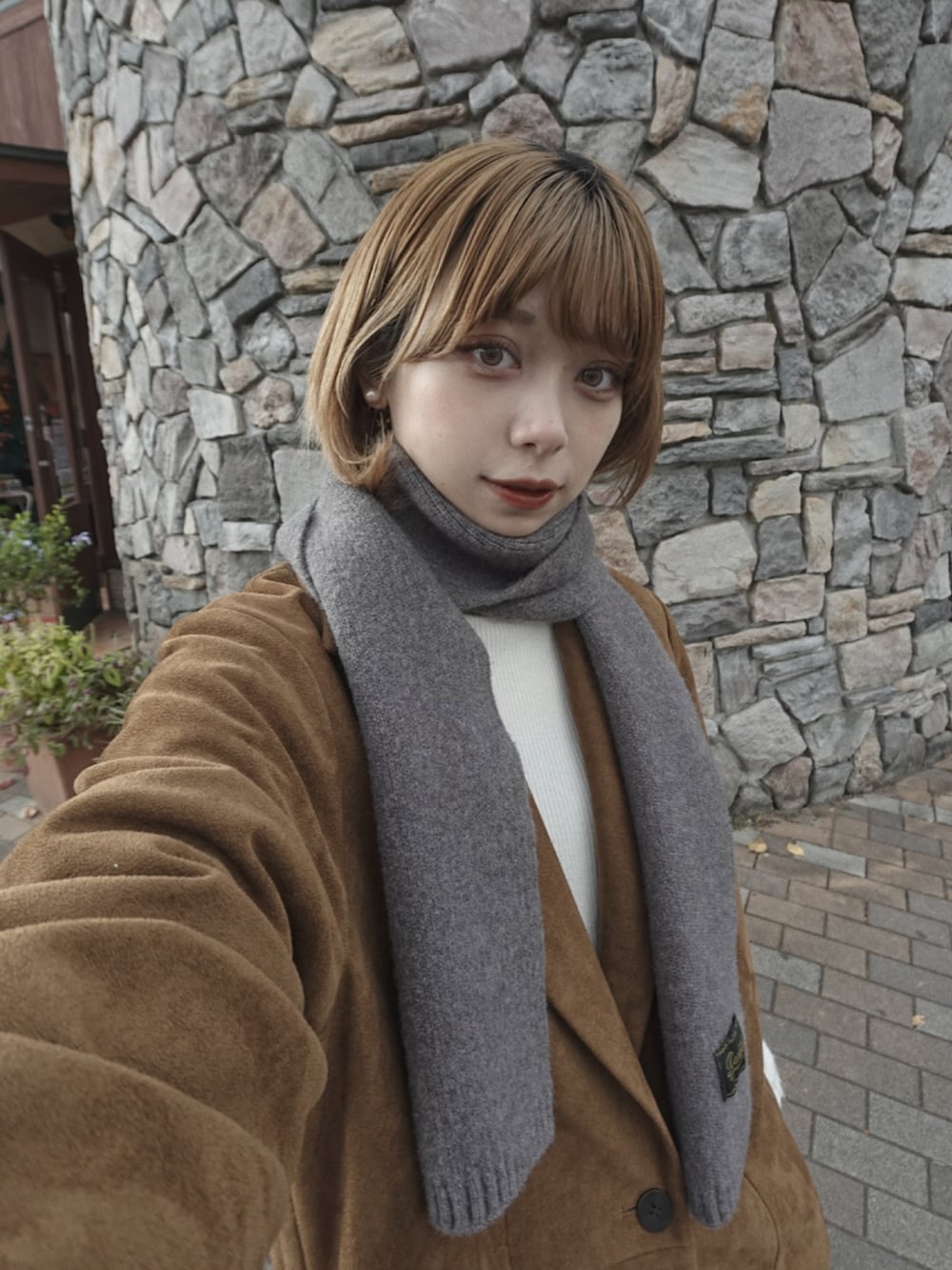 ブラウン系のテーラードジャケット、ホワイト系のトップス、ブラック系のショルダーバッグを着用したレディースの冬コーディネートの4枚目の写真