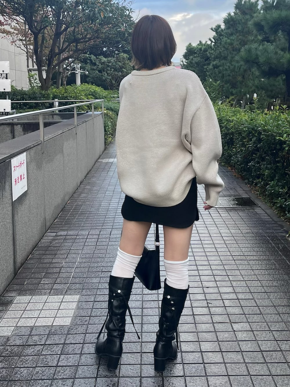 ホワイト系のニット/セーター、ブラック系のスカート、ブラック系のショルダーバッグを着用したレディースの秋コーディネートの2枚目の写真