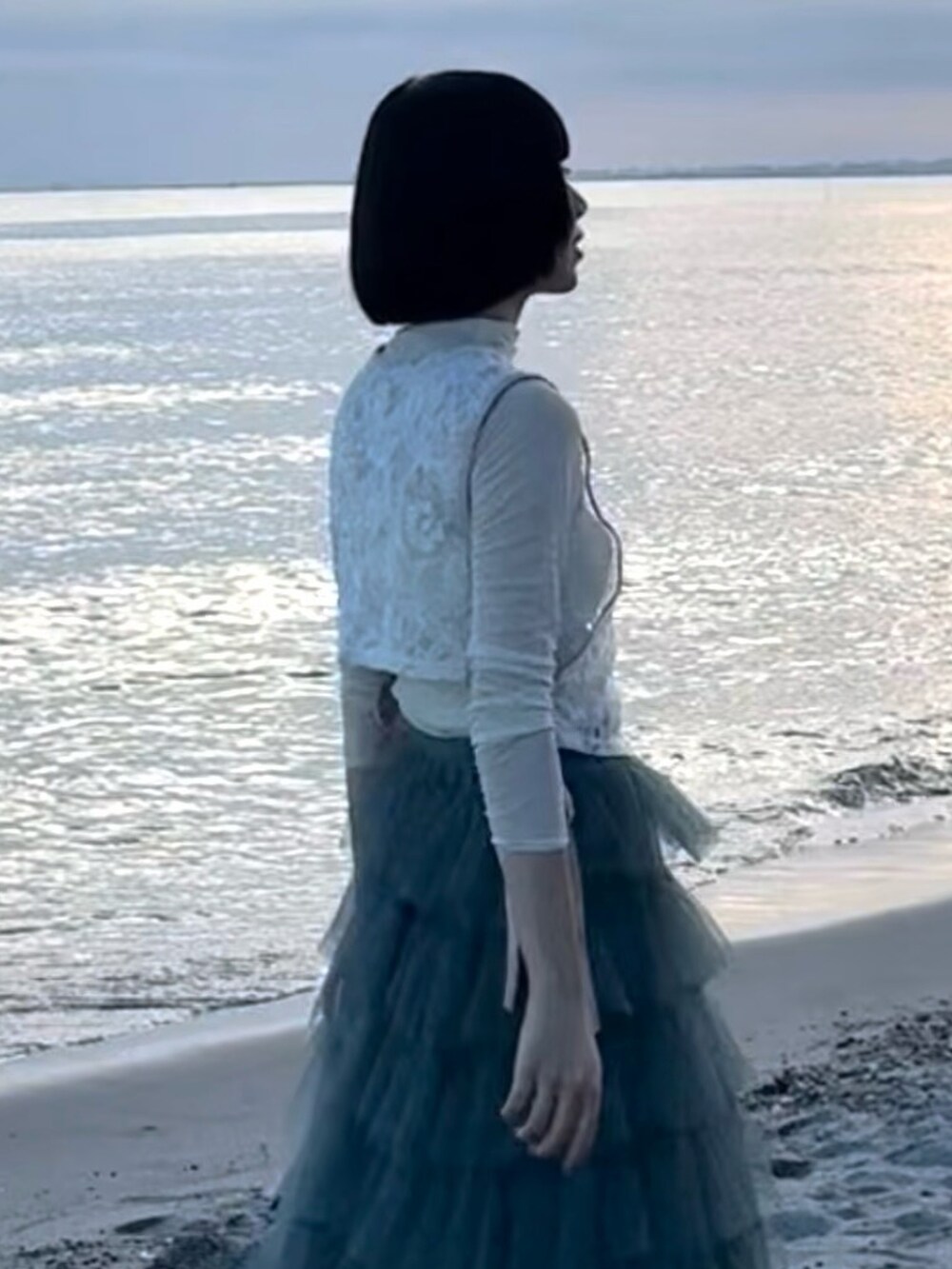 ブルー系のスカート、ブラック系のシューズ、ベージュ系のトップスを着用したレディースの夏コーディネートの5枚目の写真