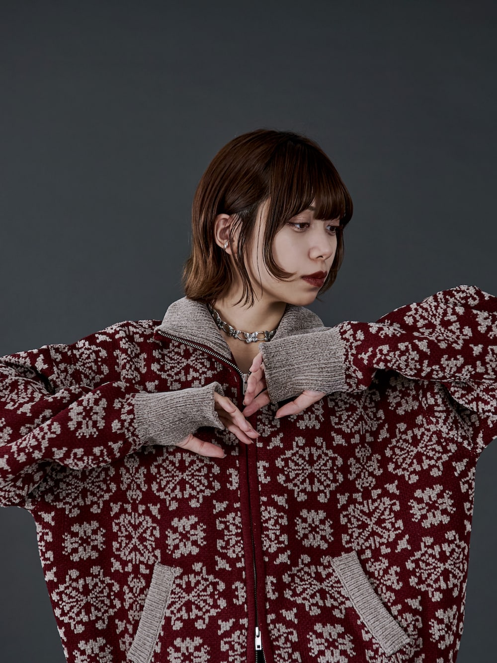 レッド系のニット/セーター、ブラック系のスラックス、ブラック系のブーツを着用したレディースの冬コーディネートの3枚目の写真