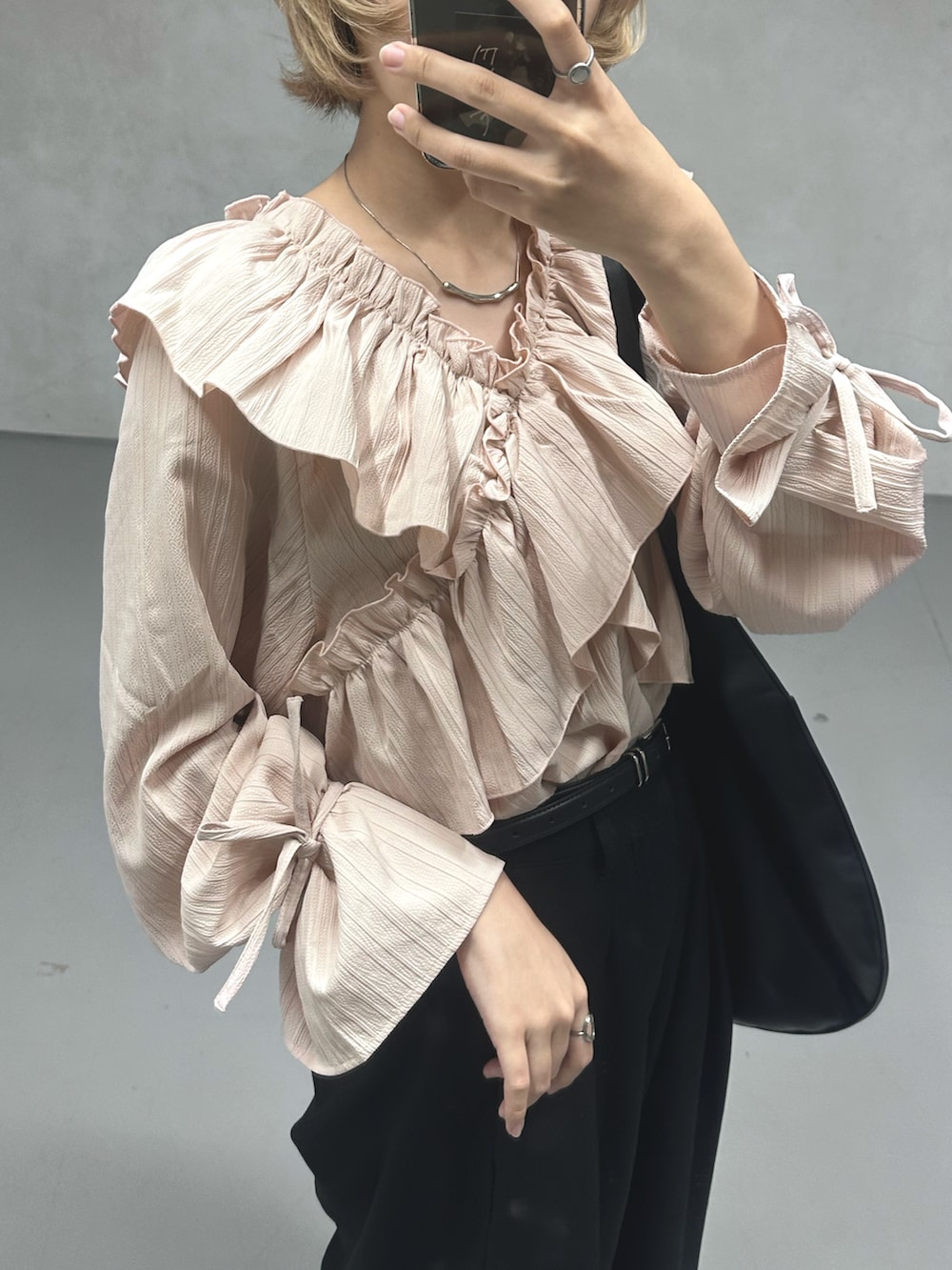 ピンク系のシャツ/ブラウス、ブラック系のトートバッグ、ブラック系のパンプスを着用したレディースの春コーディネートの2枚目の写真