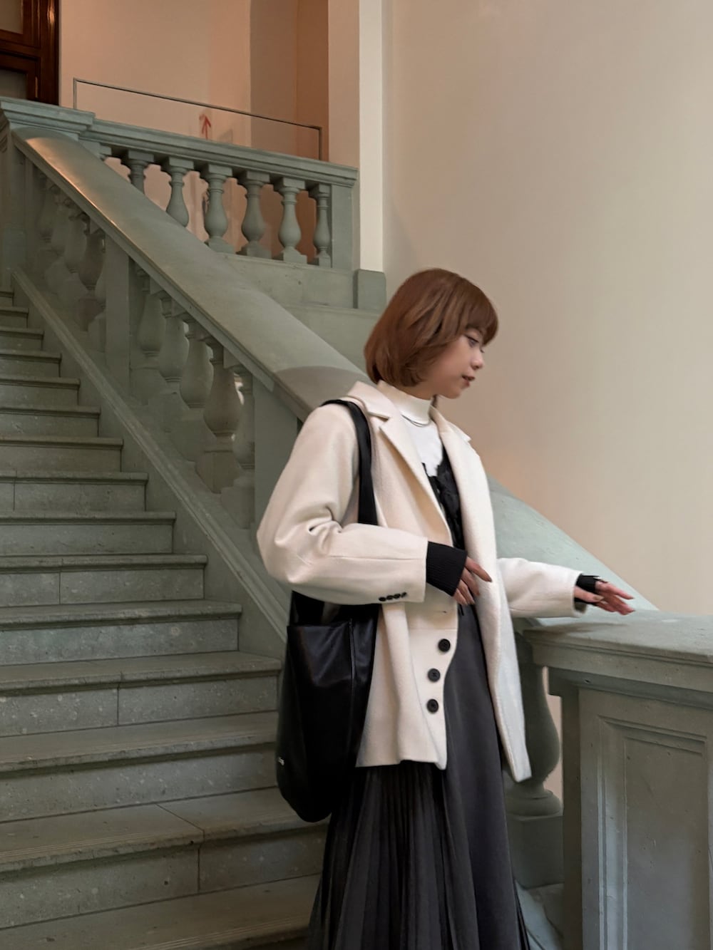 グレー系のスカート、ブラック系のローファー、ブラック系のトートバッグを着用したレディースの秋コーディネートの2枚目の写真