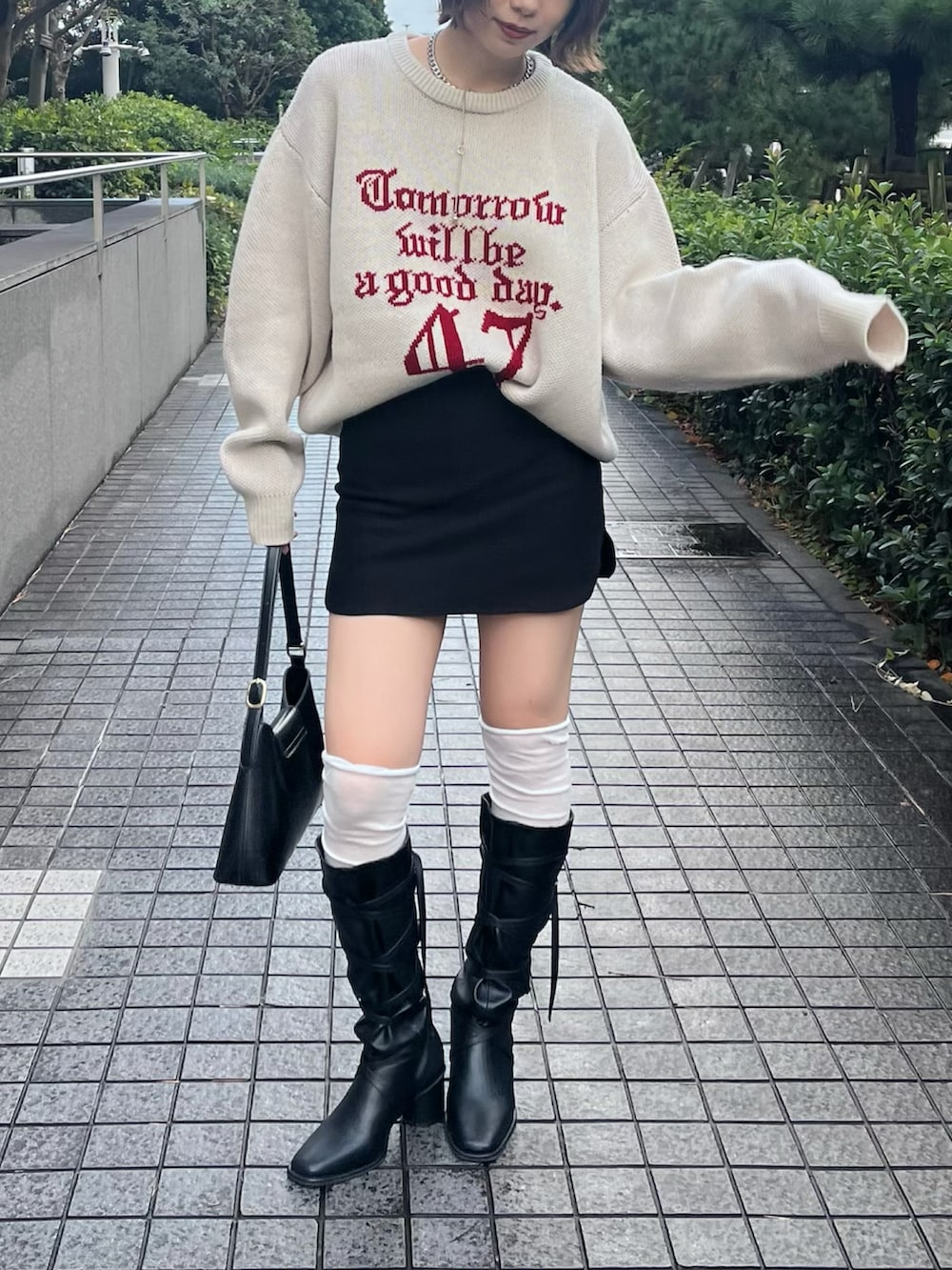 ホワイト系のニット/セーター、ブラック系のスカート、ブラック系のショルダーバッグを着用したレディースの秋コーディネートの3枚目の写真