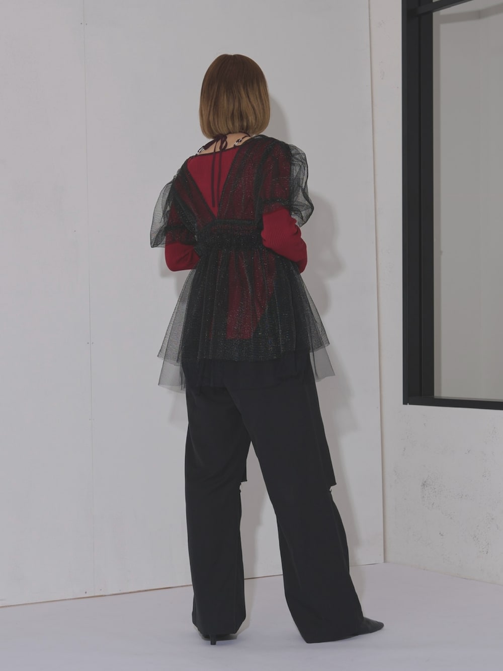 ブラック系のスラックス、パープル系のニット/セーター、ブラック系のその他トップスを着用したレディースの冬コーディネートの2枚目の写真