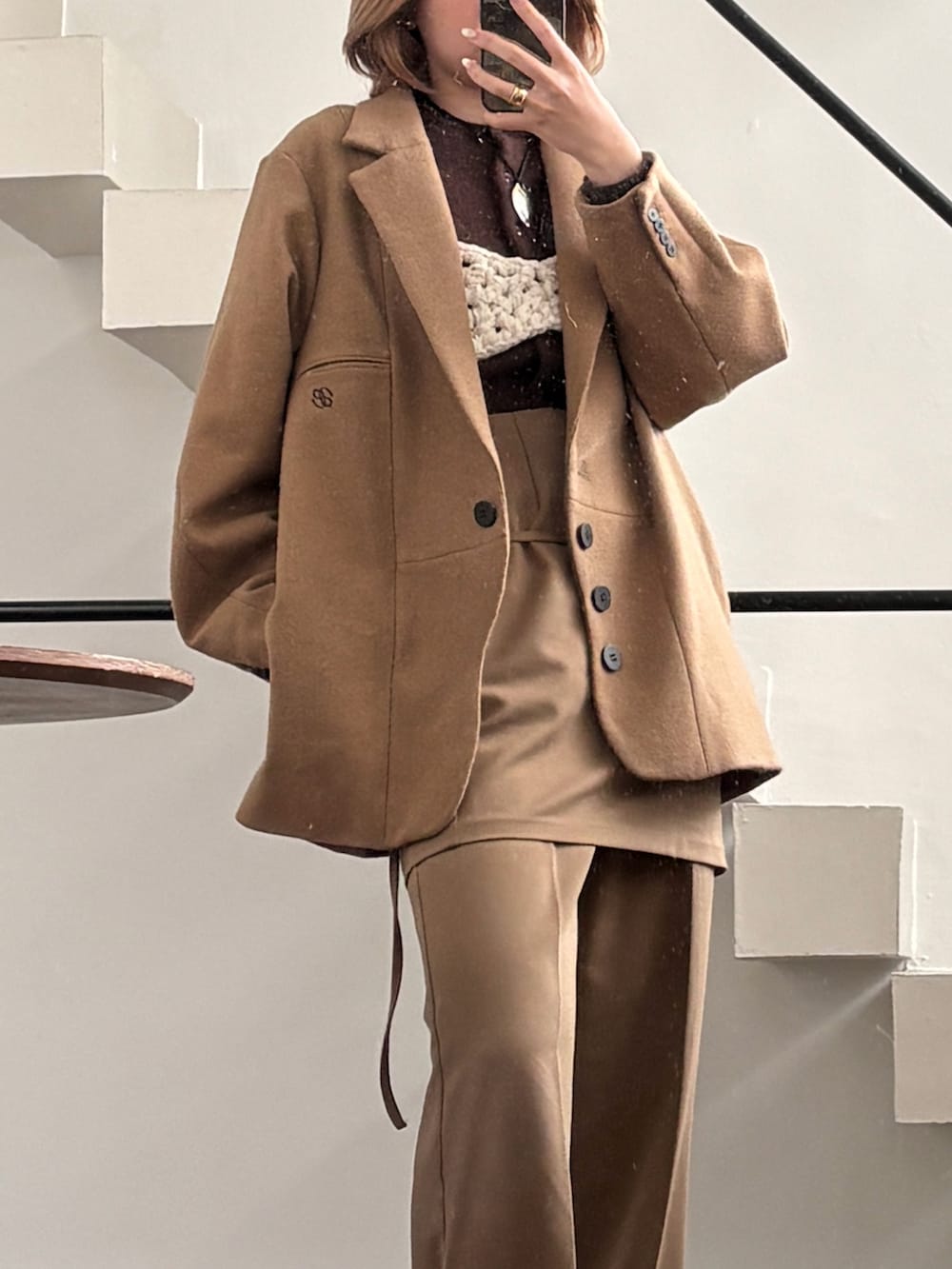 ブラウン系のパンツ、グレー系のニット/セーター、ホワイト系のジャケット/アウターを着用したレディースの冬コーディネートの4枚目の写真