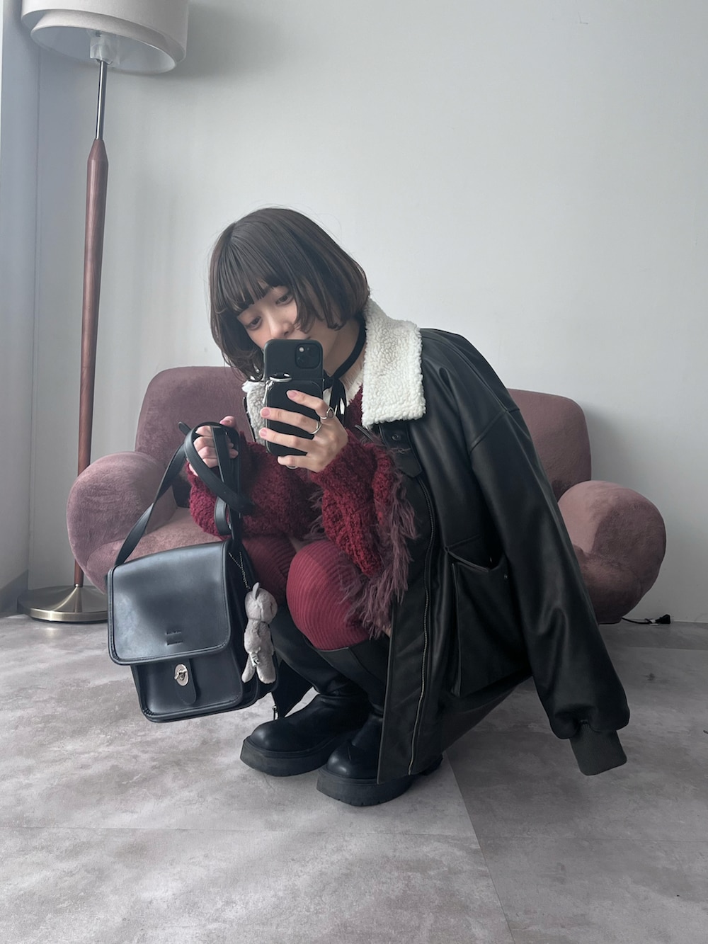 レッド系のニット/セーター、ブラック系のブルゾン、ホワイト系のワンピースを着用したレディースの冬コーディネートの2枚目の写真