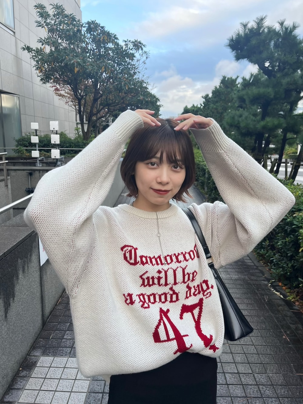 ホワイト系のニット/セーター、ブラック系のスカート、ブラック系のショルダーバッグを着用したレディースの秋コーディネートの4枚目の写真