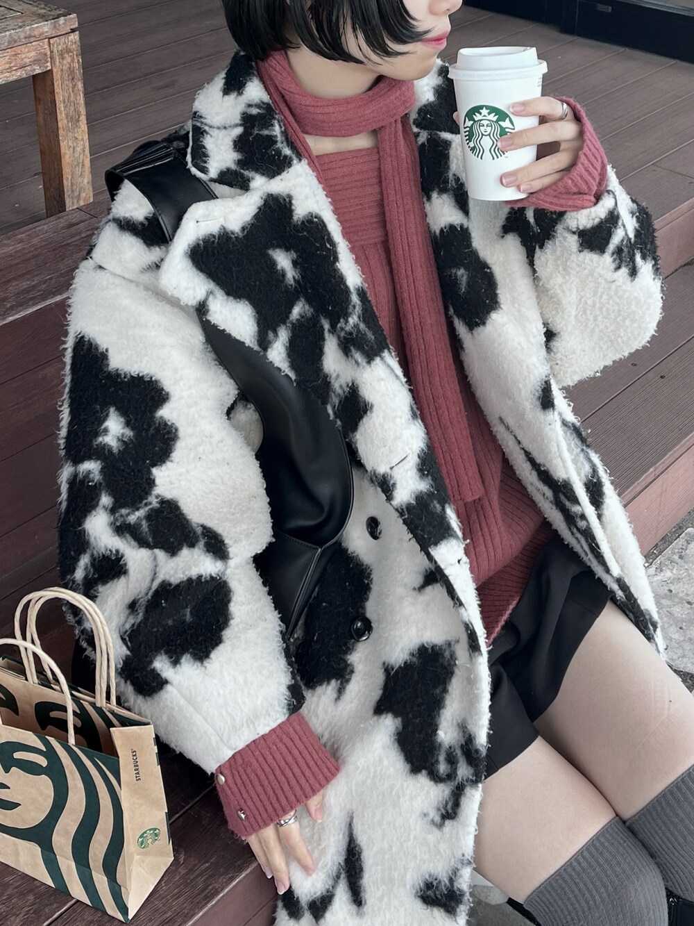 ホワイト系のチェスターコート、ピンク系のニット/セーター、ブラック系のトートバッグを着用したレディースの冬コーディネートの2枚目の写真