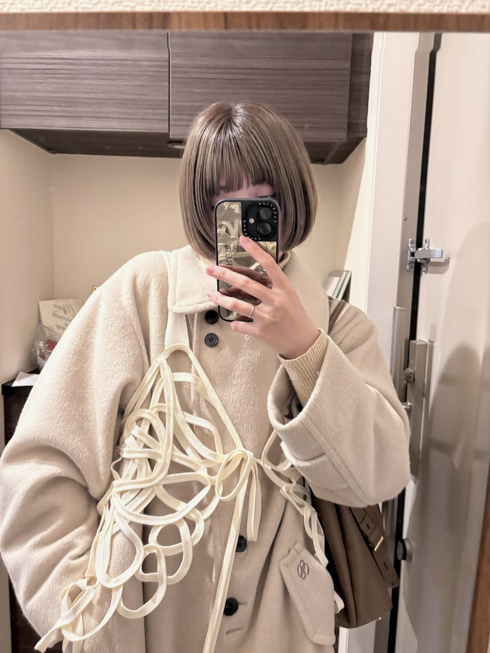 ブラック系のシューズ、ベージュ系のジャケット/アウター、ブラック系のスマホグッズを着用したレディースの春コーディネートの2枚目の写真