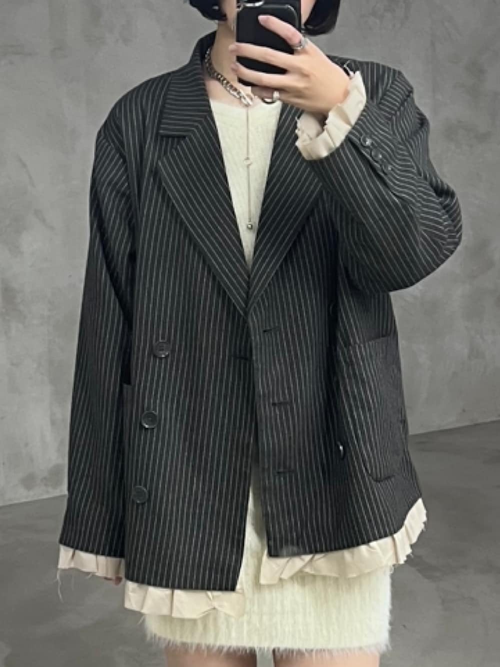 グレー系のテーラードジャケット、ホワイト系のワンピース、ブラック系のブーツを着用したレディースの春コーディネートの2枚目の写真