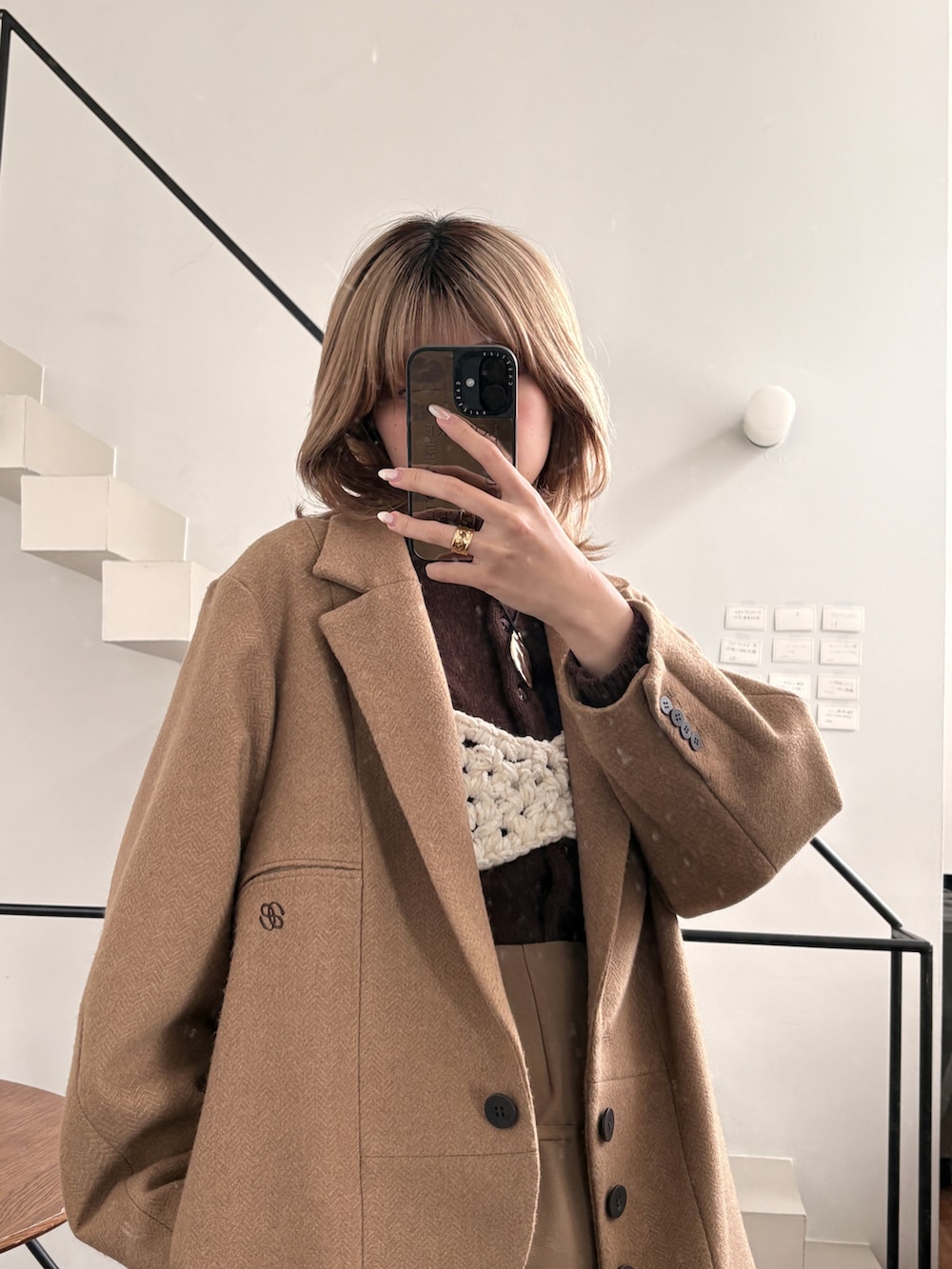 ブラウン系のパンツ、グレー系のニット/セーター、ホワイト系のジャケット/アウターを着用したレディースの冬コーディネートの3枚目の写真