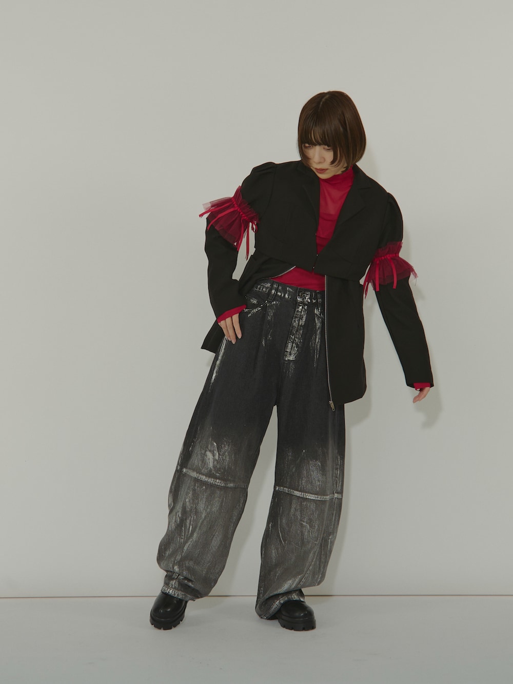 ブラック系のテーラードジャケット、レッド系のトップス、ブラック系のデニムパンツを着用したレディースの冬コーディネートの2枚目の写真