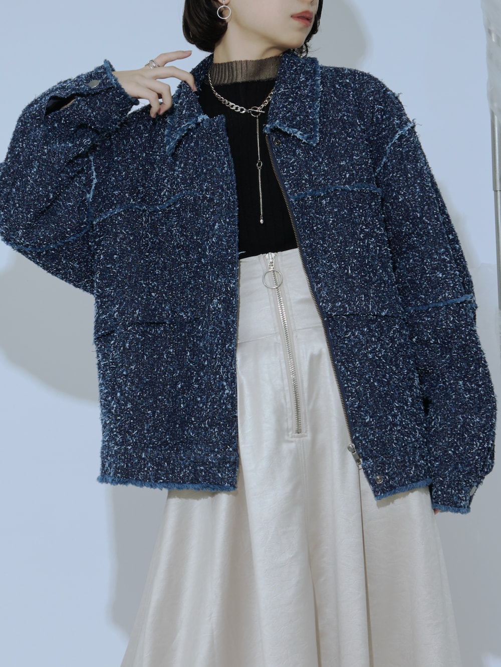 ブラック系のデニムジャケット、ベージュ系のスカート、ブラック系のニット/セーターを着用したレディースの冬コーディネートの2枚目の写真