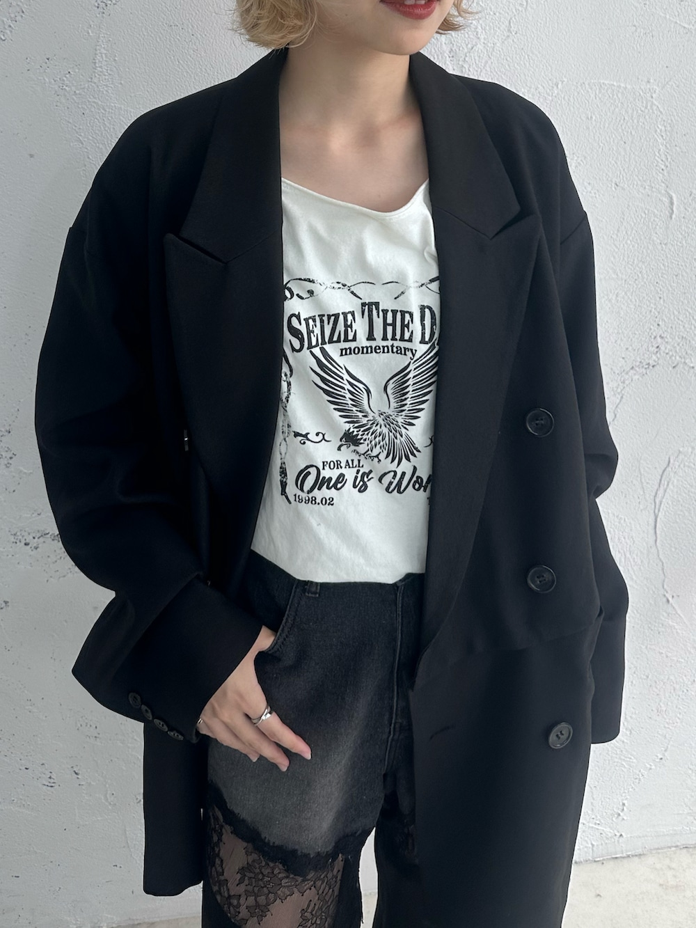 ホワイト系のトップス、ブラック系のテーラードジャケット、ブラック系のデニムパンツを着用したレディースの春コーディネートの3枚目の写真