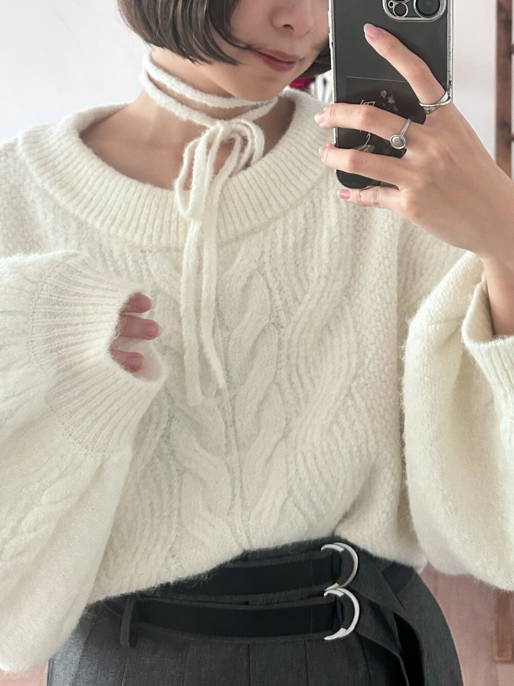 グレー系のスカート、シルバー系のブーツ、ホワイト系のニット/セーターを着用したレディースの冬コーディネートの4枚目の写真