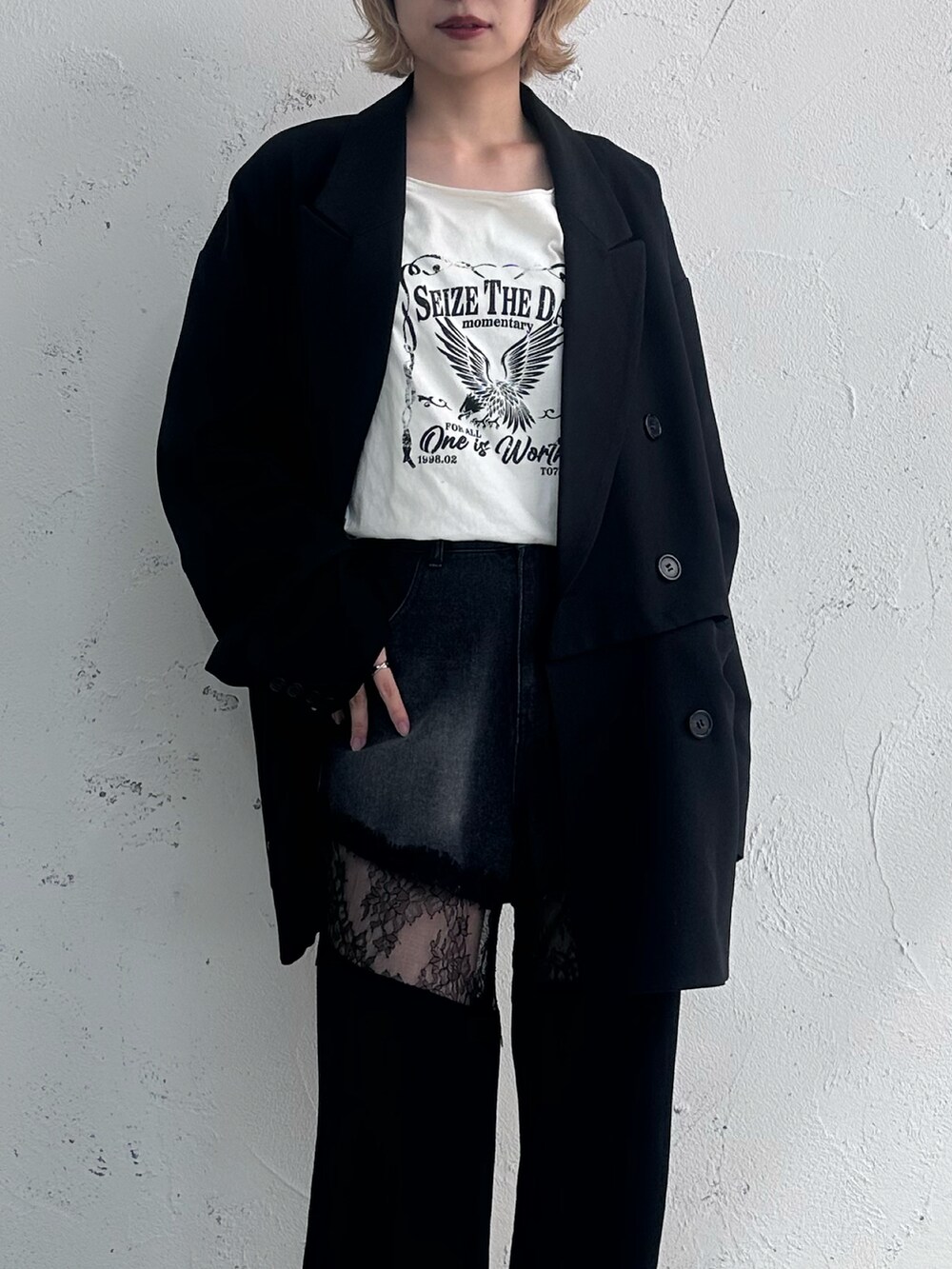 ホワイト系のトップス、ブラック系のテーラードジャケット、ブラック系のデニムパンツを着用したレディースの春コーディネートの2枚目の写真