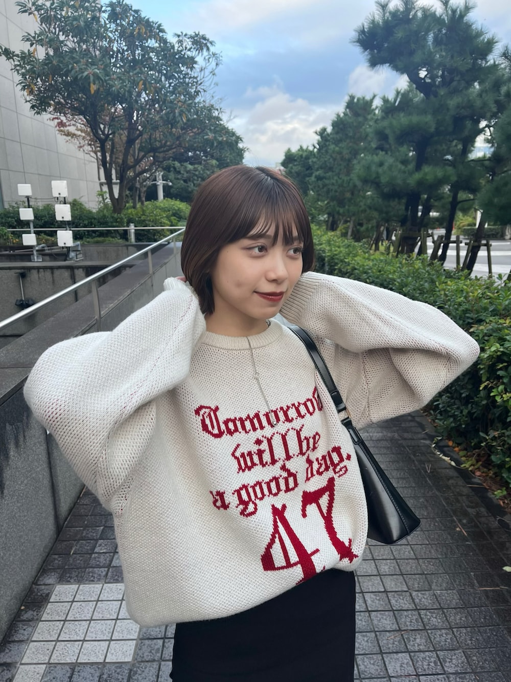 ホワイト系のニット/セーター、ブラック系のスカート、ブラック系のショルダーバッグを着用したレディースの秋コーディネートの5枚目の写真