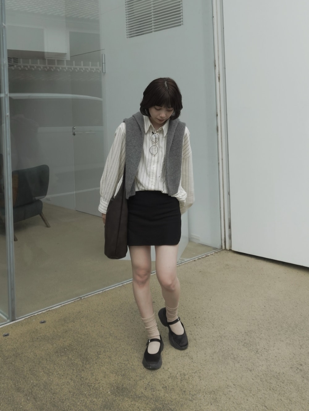 ベージュ系のシャツ/ブラウス、グレー系のニット/セーター、ブラック系のスカートを着用したレディースの秋コーディネートの4枚目の写真