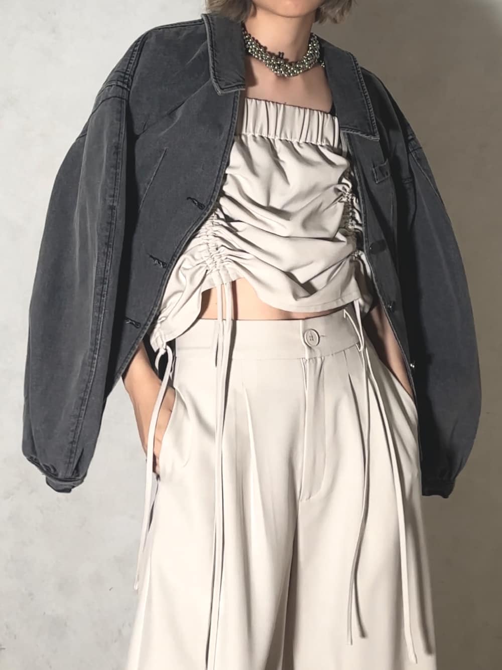 グレー系のデニムジャケット、ブラック系のスラックスを着用したレディースの夏コーディネートの2枚目の写真