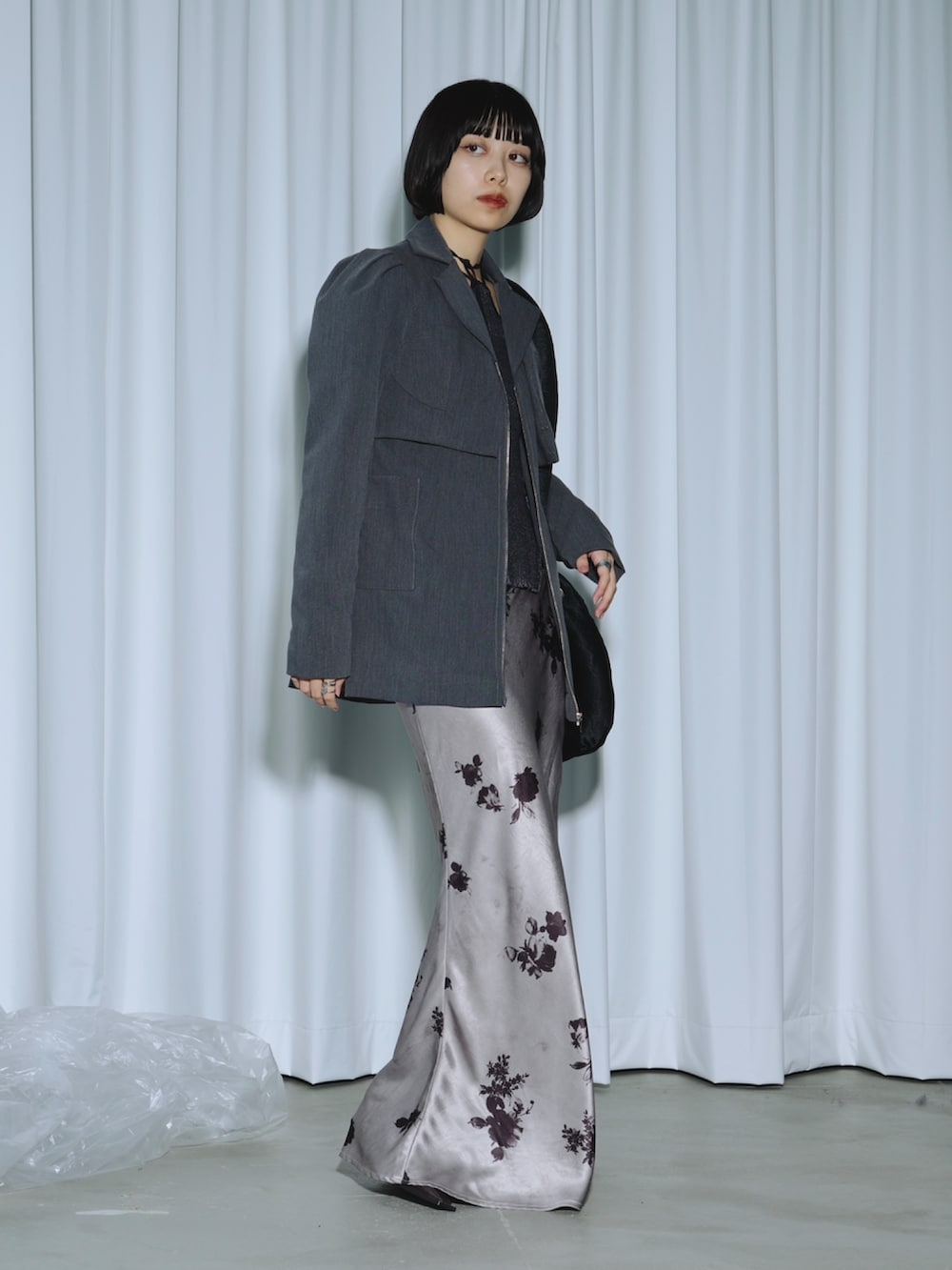 ブラック系のテーラードジャケット、パープル系のニット/セーター、パープル系のスカートを着用したレディースの春コーディネートの2枚目の写真