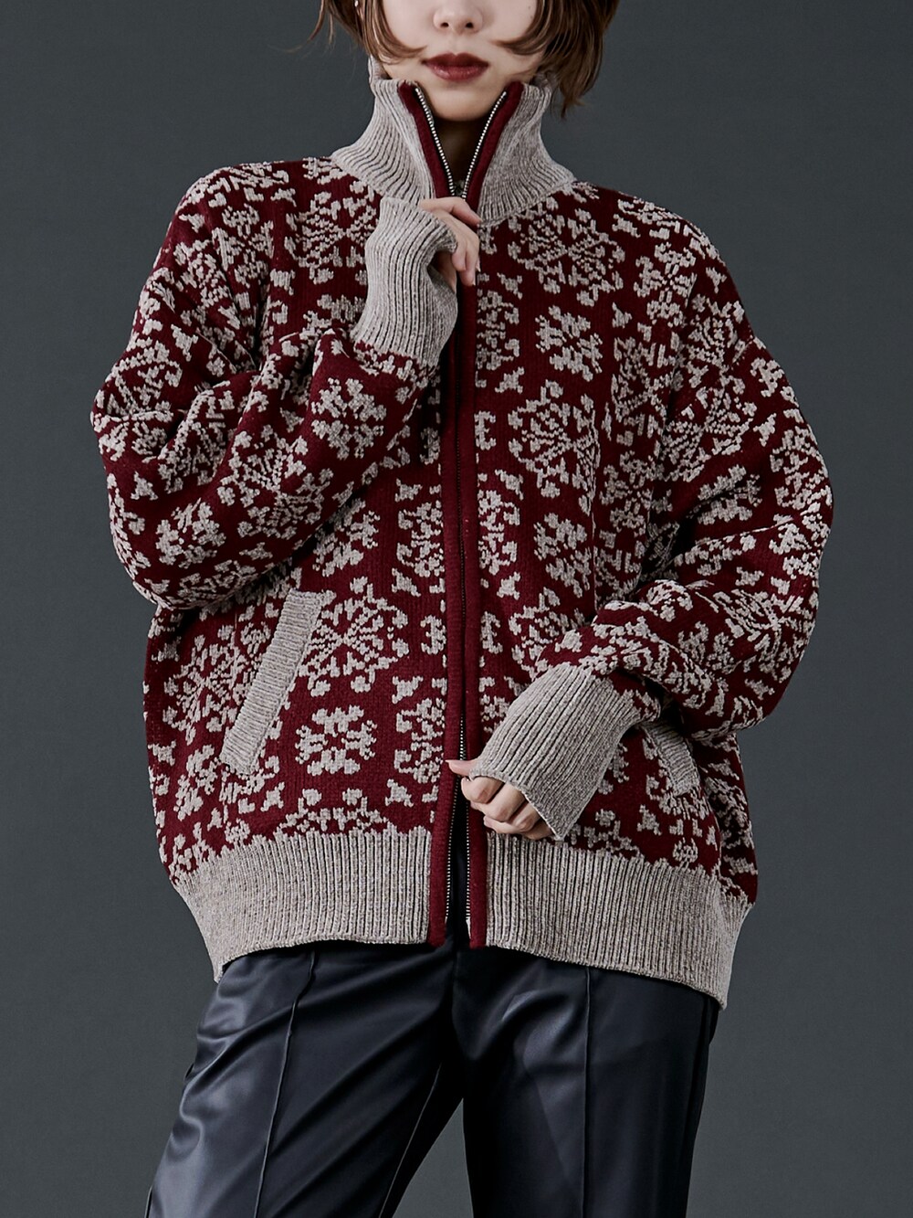 レッド系のニット/セーター、ブラック系のスラックス、ブラック系のブーツを着用したレディースの冬コーディネートの2枚目の写真