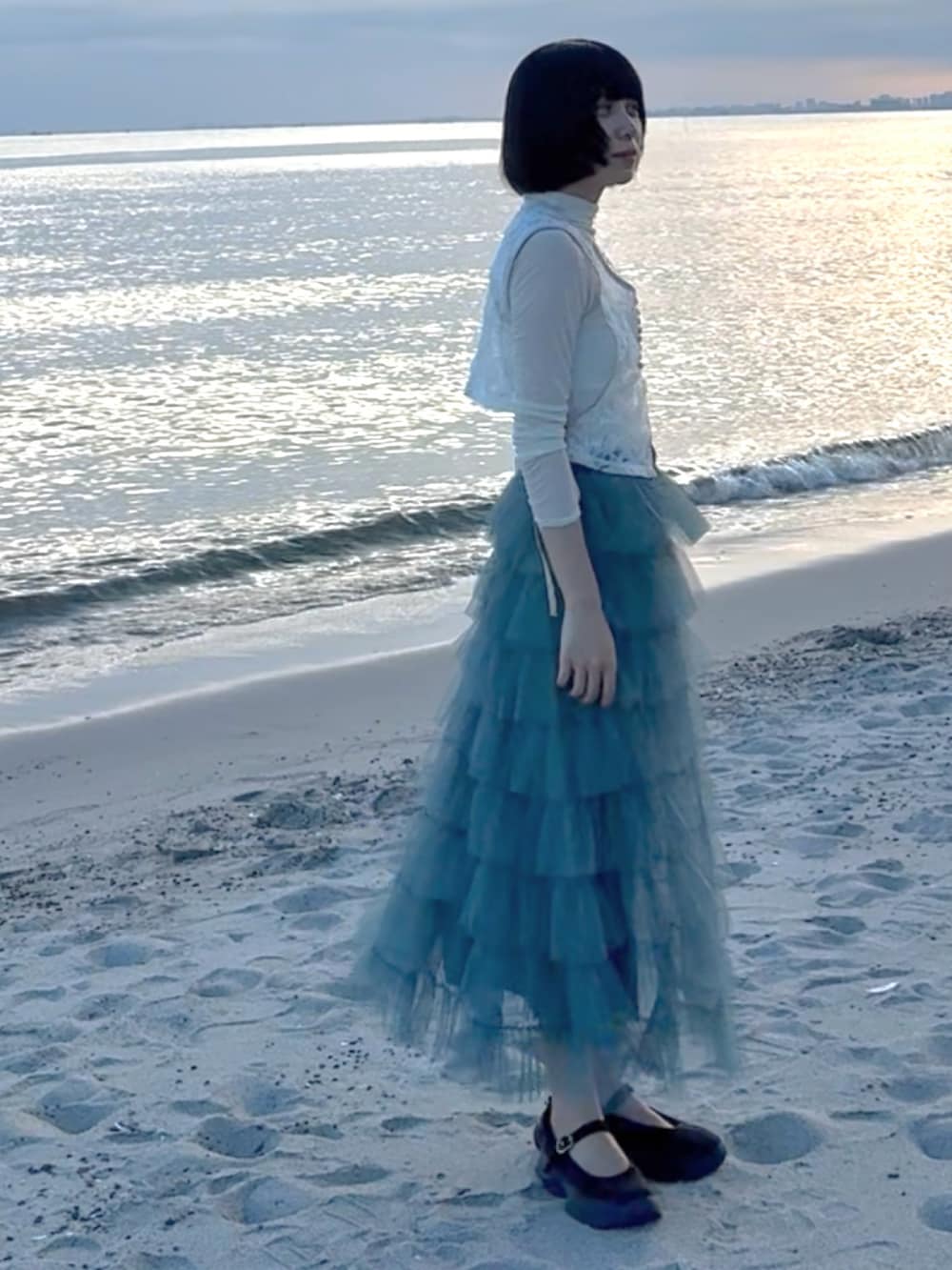 ブルー系のスカート、ブラック系のシューズ、ベージュ系のトップスを着用したレディースの夏コーディネートの2枚目の写真