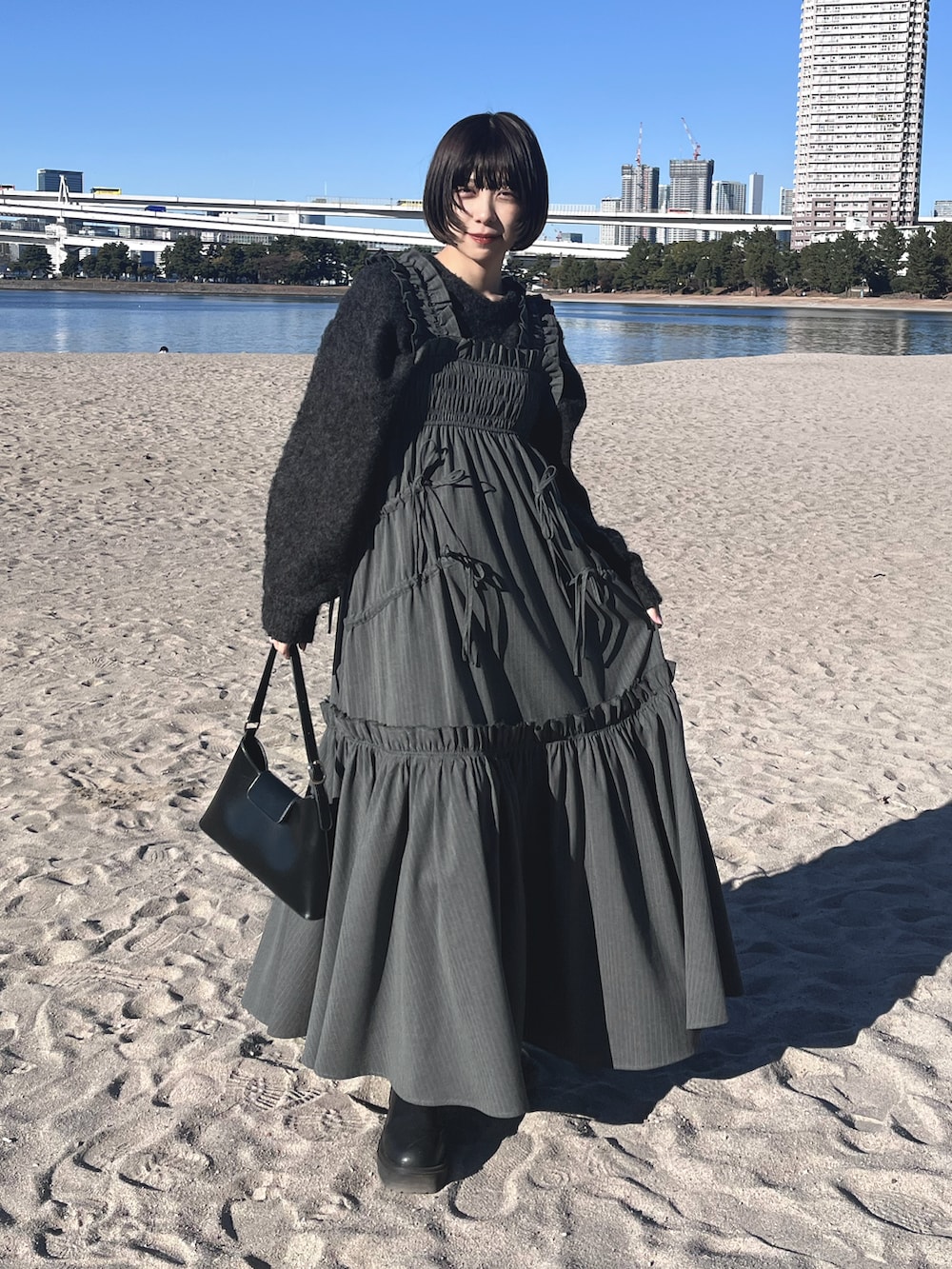 ブラック系のショルダーバッグ、グレー系のワンピース、グレー系のニット/セーターを着用したレディースの冬コーディネートの2枚目の写真