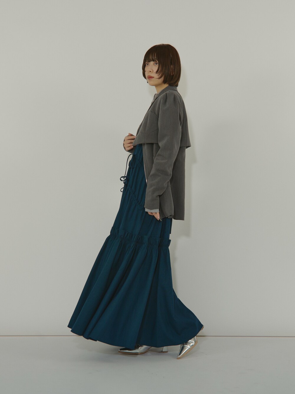 ブルー系のワンピース、ブラック系のテーラードジャケット、シルバー系のブーツを着用したレディースの冬コーディネートの3枚目の写真