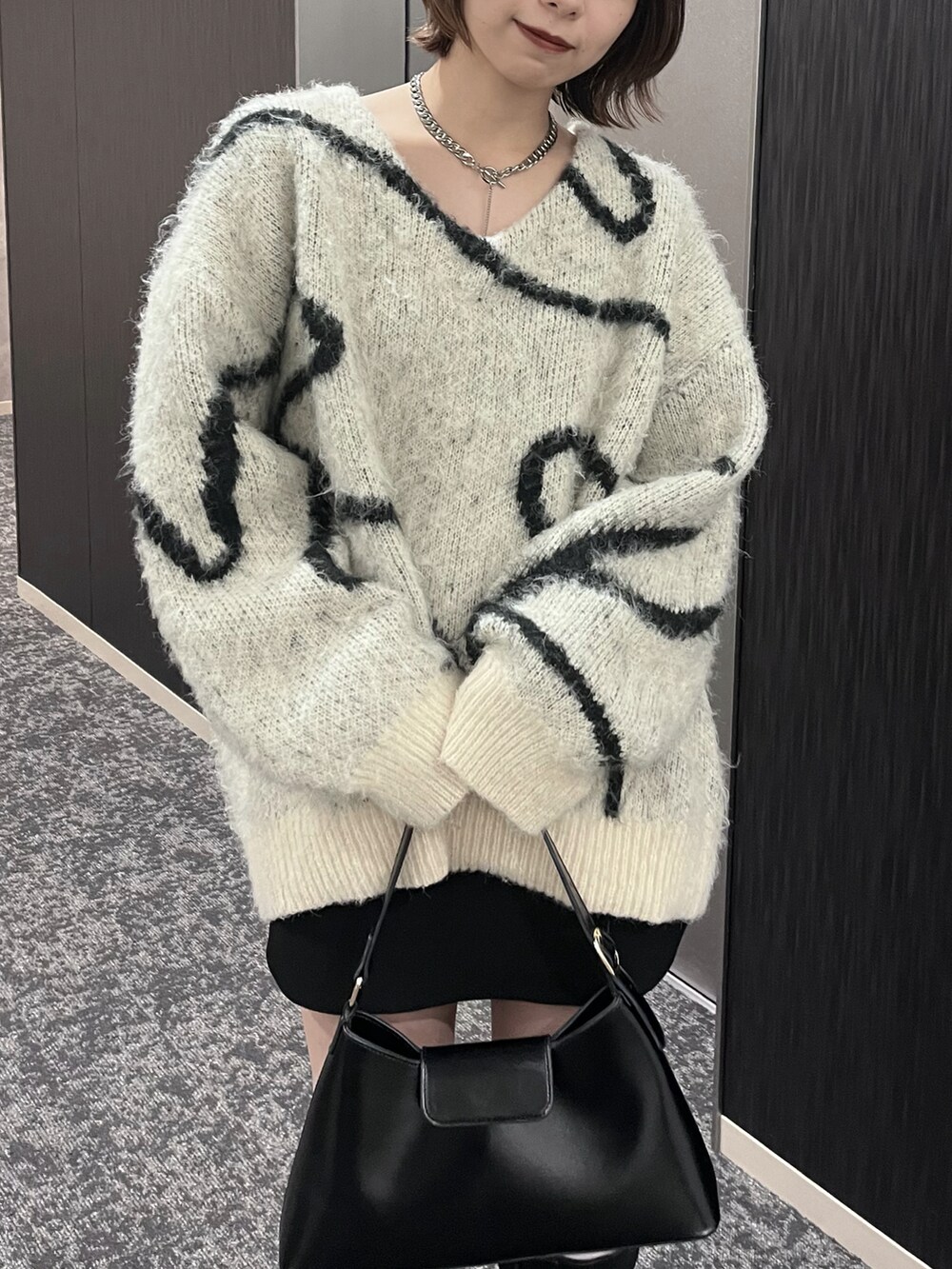 ブラック系のショルダーバッグ、ブラック系のブーツ、その他のニット/セーターを着用したレディースの秋コーディネートの2枚目の写真