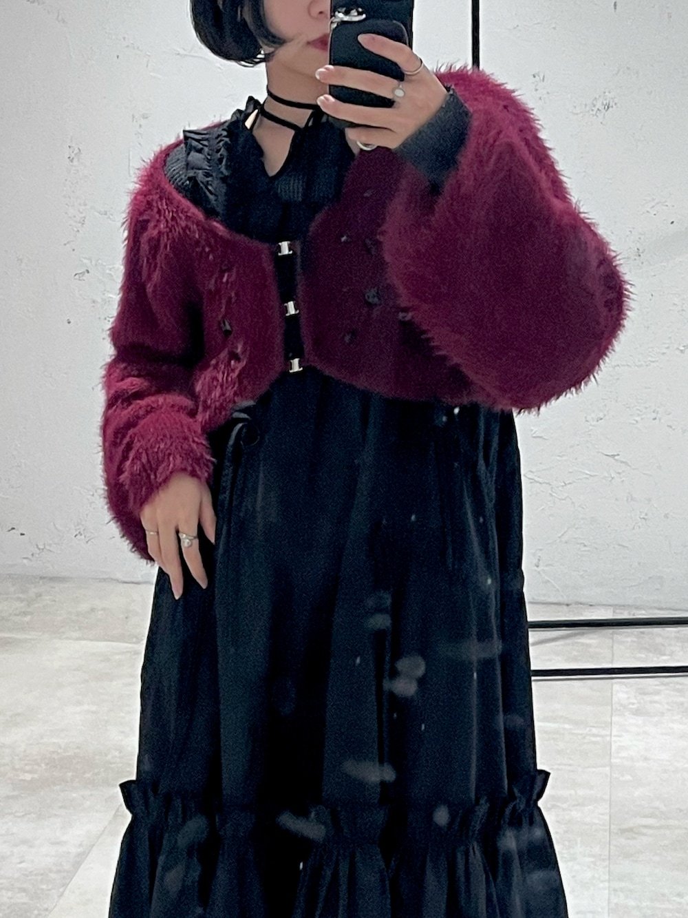 ブラック系のワンピース、レッド系のカーディガン/ボレロ、ブラック系のスマホケース/カバーを着用したレディースの冬コーディネートの2枚目の写真